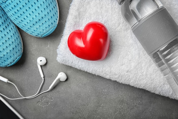 Gym stuff and red heart on grey background Cardio training concept