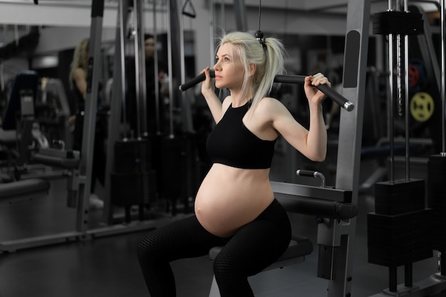 Gym workout Pregnant woman sportswear training shoulders with exercise machine Beautiful pregnancy time