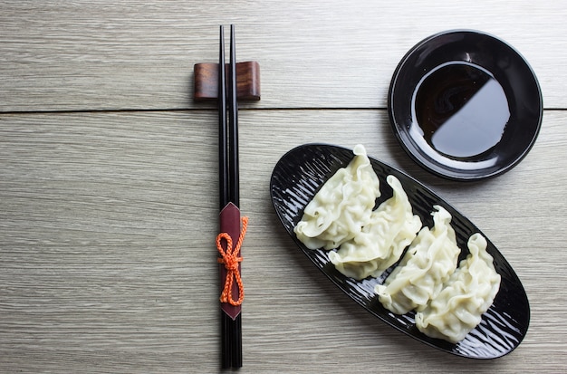 Gyoza on black plate with chopsticks top view