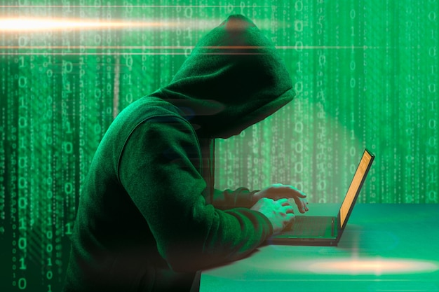 Hacker attack Faceless hooded anonymous computer hacker hacker man with laptop attack to server network system online in data internet security hacking concept dark green background