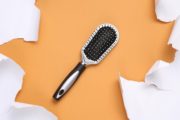 Hair brush and white torn paper sheets on beige background Minimalistic background Top view Copy space