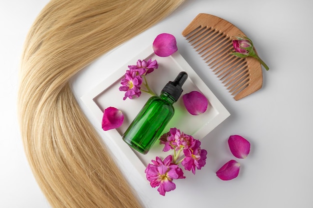 A hair care oil or serum in green dropper bottle lying on a white ceramic tray with rose petals around it product marketing mockup A concept of hair care in a salon or at home