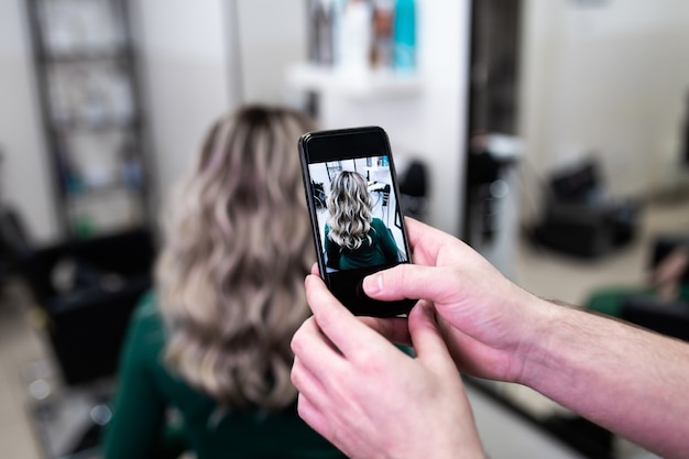 Hair dresser taking photo of mature woman hairstyle after dying hair and making highlights in hair salon.