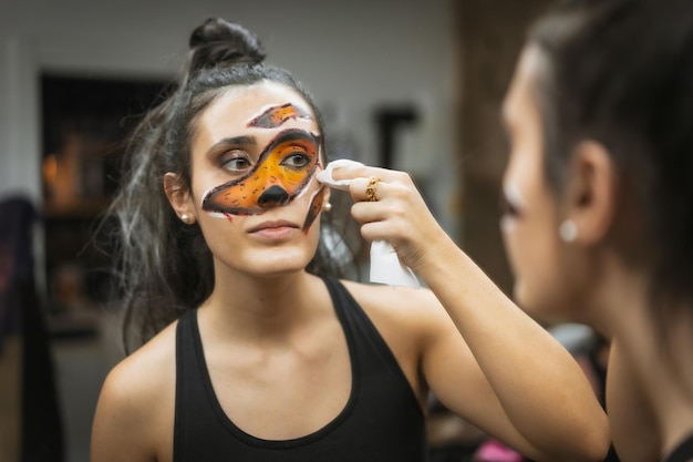 Hair and makeup preparations for the Halloween party applying a paint on the face