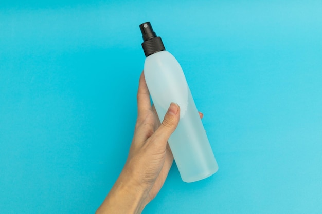 Hair spray in blue plastic bottle on blue background monochrome