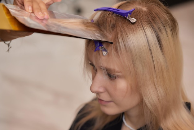 Hair stylist makes bouffant using comb on thin strands Shatush technique for hair lightening