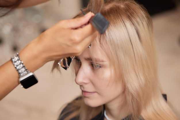 Hair stylist makes bouffant using comb on thin strands Shatush technique for hair lightening