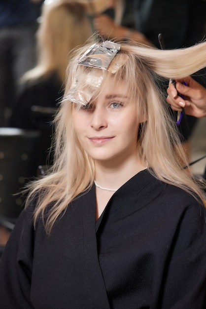 Hair stylist makes bouffant using comb on thin strands Shatush technique for hair lightening