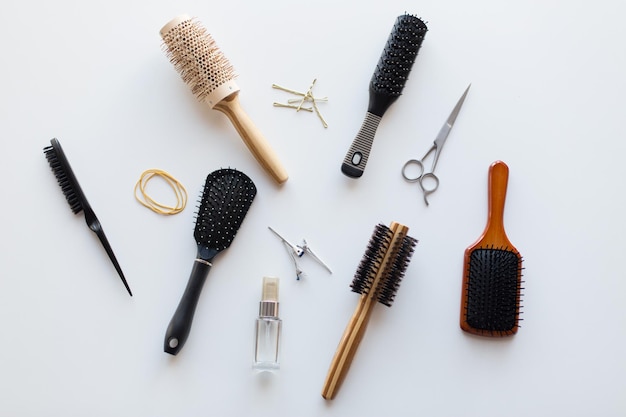 hair tools, beauty and hairdressing concept - scissors, different brushes, pins and styling spray on white background