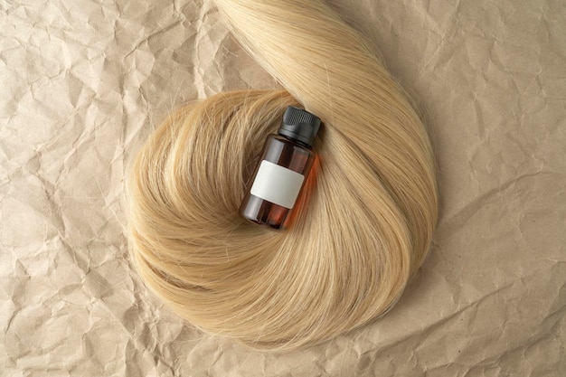 A hair treatment essential oil for smoothing hair lying on a strand of blond hair