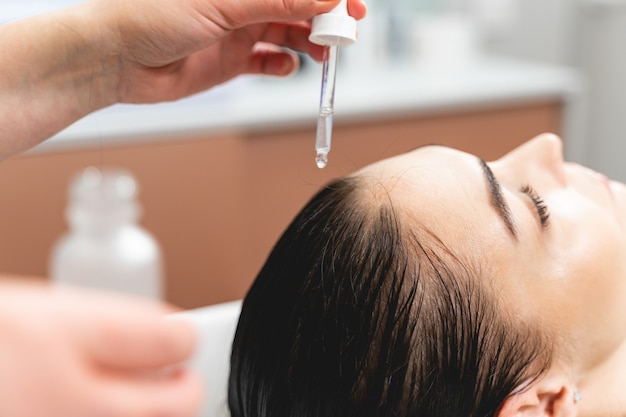 Hair treatment. Kind young woman leaning her head on sink while doing mask for hair