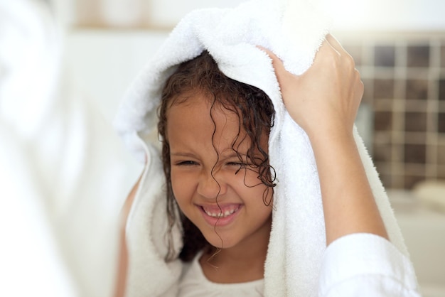 Haircare routine cleaning and hair being washed by a mother for her happy carefree and smiling daughter at home Loving caring and kind parent helping her child get dressed get dry or get clean