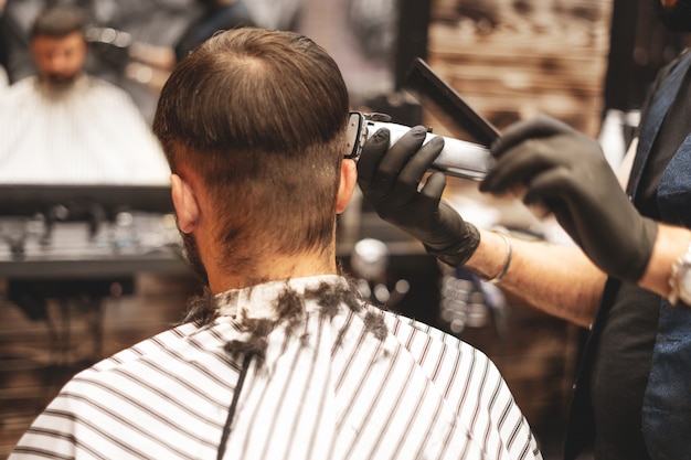 Haircut head in barbershop. Barber cuts the hair on the head of the client. The process of creating hairstyles for men. Barber shop. Selective focus.