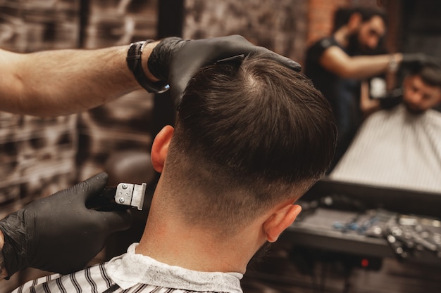 Haircut head in barbershop. Barber cuts the hair on the head of the client. The process of creating hairstyles for men. Barber shop