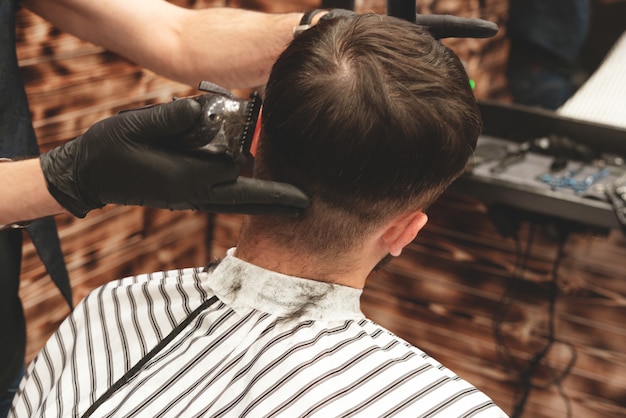 Haircut head in barbershop. Barber cuts hair on head of  client. The process of creating hairstyles for men. Barber shop