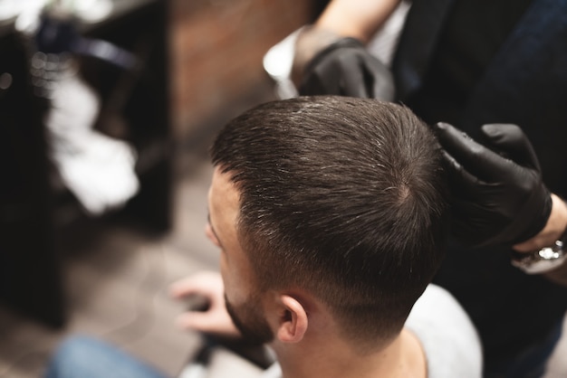 Haircut head in barbershop. Barber cuts the hair on the head of the client. The process of creating hairstyles for men.