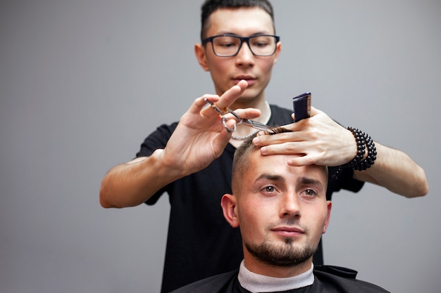 hairdresser cuts a young guy's hair in a barbershop