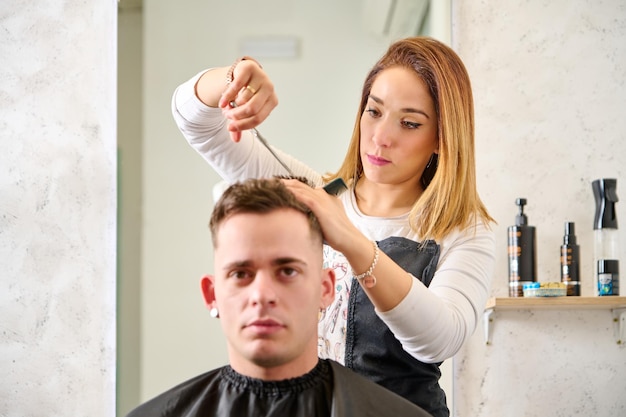 Hairdresser cutting hair and styling a client in the barbershop