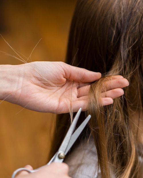 Hairdresser cutting little girl's hair