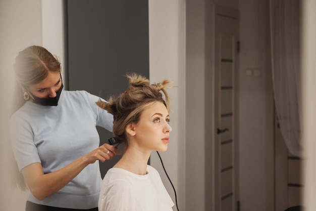 Hairdresser does hairstyle cute pretty young woman in beauty salon