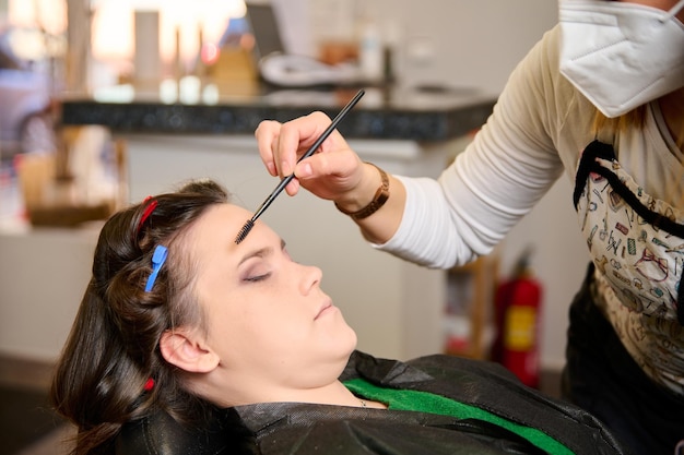 hairdresser doing makeup and styling a young female client in a beauty salon