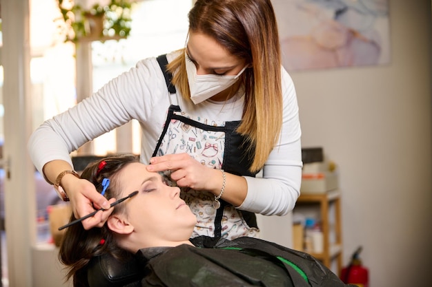 hairdresser doing makeup and styling a young female client in a beauty salon