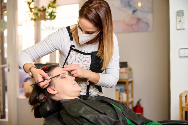 hairdresser doing makeup and styling a young female client in a beauty salon