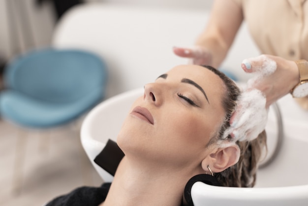 Hairdresser giving a head massage to a caucasian client