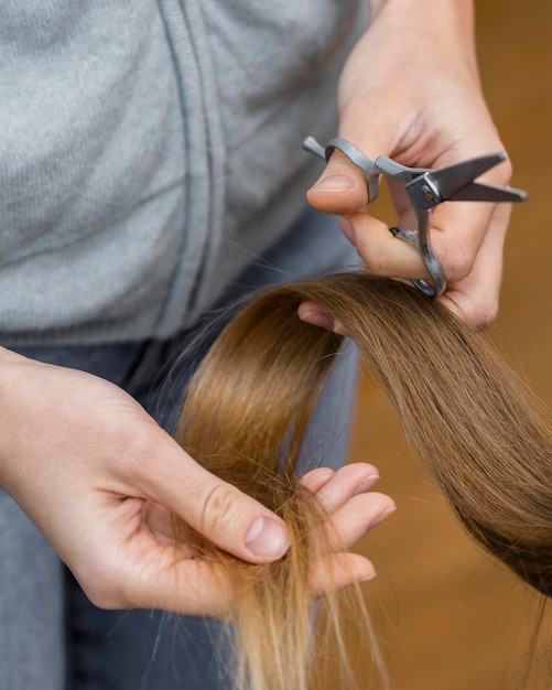 Hairdresser holding lock of hair and scissors