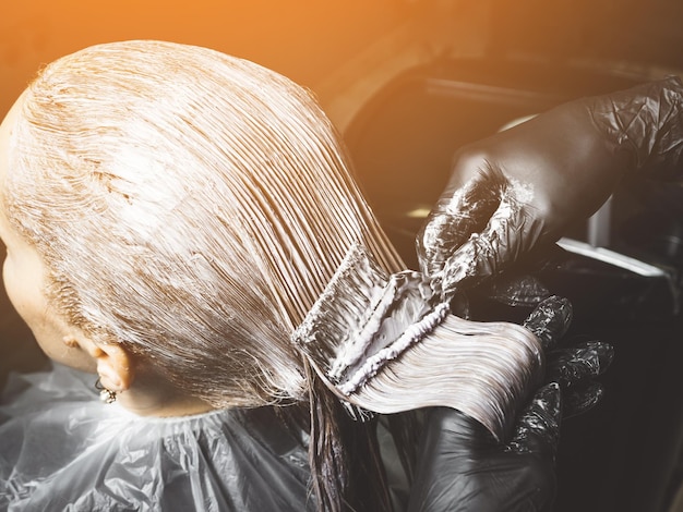 Photo hairdresser is applying bleaching powder on womans hair