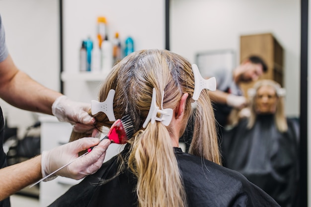 Hairdresser is dying hair roots of mature woman.