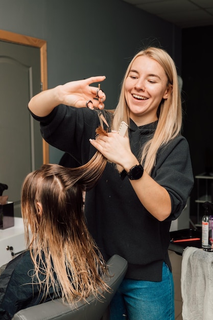 The hairdresser lifted a strand of hair up and cut off the length