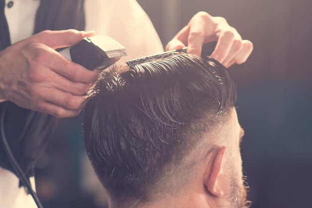 Hairdresser makes hairstyle a man with a beard