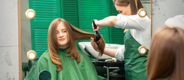 Hairdresser making hairstyling for the woman while combing with hairbrush, comb in a hair salon.