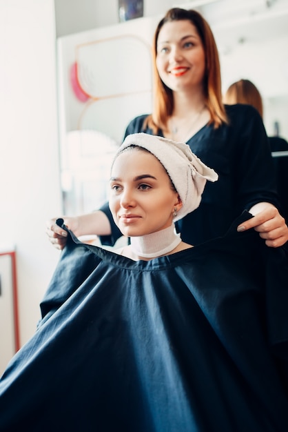 Hairdresser picks up the cape on female client