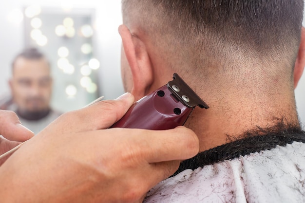 The hairdresser removes hairs with an electric razor