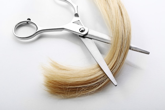 Hairdresser's scissors with strand of blonde hair, isolated on white