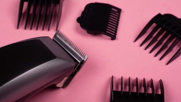 Hairdresser's tool. hair clipper close-up on a pink background with nozzles of different sizes.