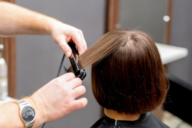 Hairdresser straightens hair of woman