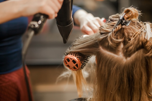 Hairdresser stylist dries wet hair with hair dryer