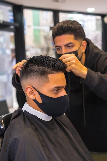 Hairdresser with face mask cutting hair