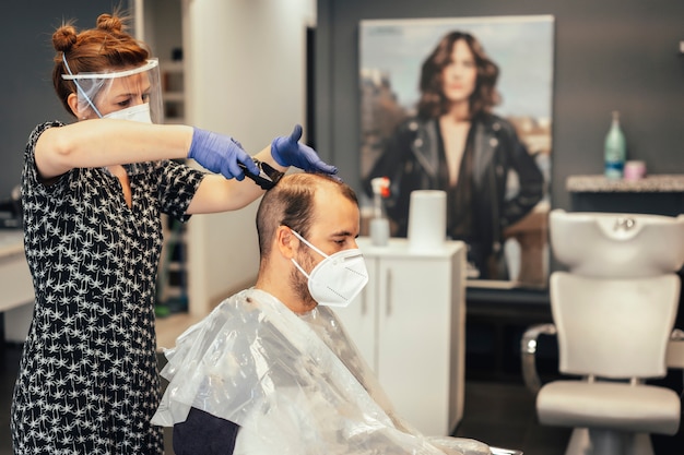 Hairdresser with security measures by the covid-19, new normality, social distance, portraits of hairdresser and client with mask