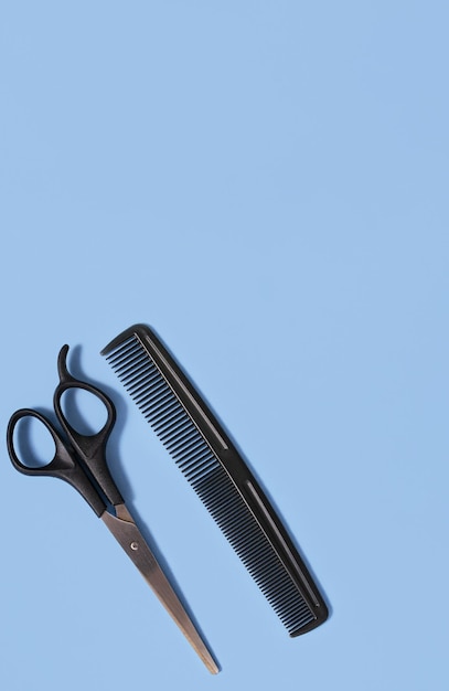 Hairdressing scissors and a comb on a blue background The concept of a hairdresser Copy space