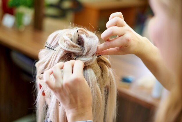 Hairdressing services. Сreating an evening hairstyle. Hair styling process.