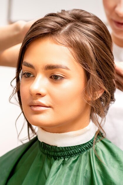 Hairstyling bride A female hairdresser makes styling hair for the beautiful young caucasian woman in a beauty salon