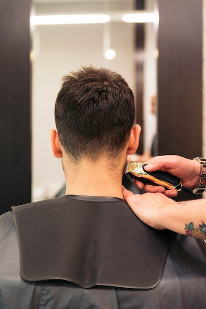 Hairstylist making men's haircut to an attractive man in the beauty salon