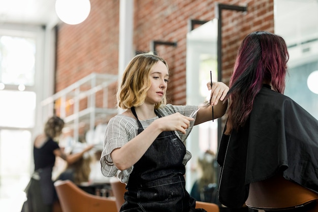 Hairstylist trimming hair of the customer in a beauty salon