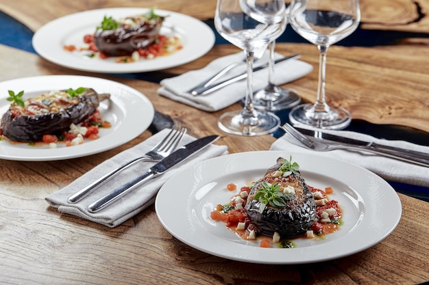 Half baked eggplants with meat, cheese and tomatoes on white background. Banquet festive dishes. Gourmet restaurant menu. White background.