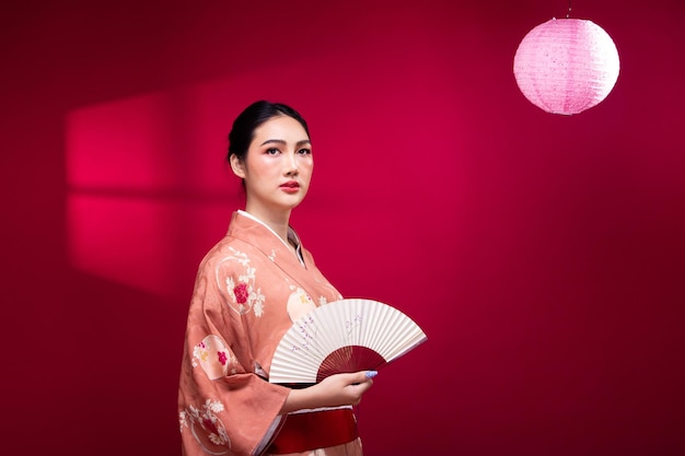 Half body Young 20s Asian Japanese woman wear Pink traditional Kimono hold art fan and lamp