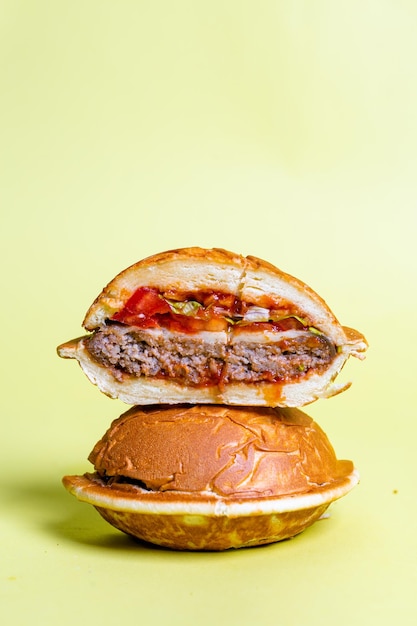 Half of burger with no top bread isolated on pastel yellow background